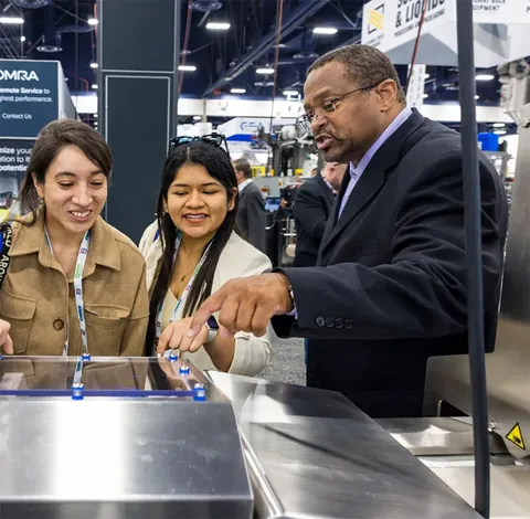 Archive photograph of attendees discussing equipment at PACK EXPO Las Vegas
